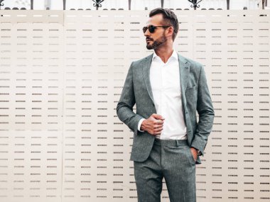 Yakışıklı, kendine güvenen, stil sahibi, Lambersex modelinin portresi. Zarif takım elbise giymiş modern bir adam. Moda erkeği gün batımında Avrupa şehrinin arka planında poz veriyor. Güneş gözlükleriyle