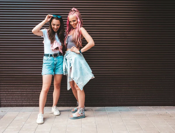 流行の夏服で2人の若い美しい笑顔のヒップスター女性 ピンクの髪で通りにポーズ性的屈託のない女性 正の純粋なモデルは 日没で楽しんでいます 陽気で幸せ — ストック写真