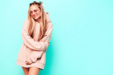 Son moda yaz kapüşonlu güzel, gülümseyen bir kadın. Stüdyoda mavi duvarın yanında poz veren kaygısız seksi kadın. Pozitif sarışın model eğleniyor ve deliriyor. Neşeli ve mutlu