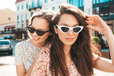 Son moda yaz kıyafetleri içinde iki güzel gülümseyen hippi kadın. Sokakta poz veren kaygısız kadınlar. Pozitif saf modeller gün batımında eğleniyor, sarılıyor ve deliriyor. Mutlu ve neşeli.