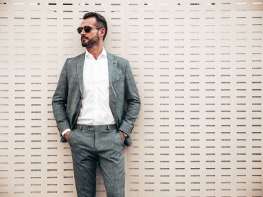 Yakışıklı, kendine güvenen, stil sahibi, Lambersex modelinin portresi. Zarif takım elbise giymiş modern bir adam. Moda erkeği gün batımında Avrupa şehrinin arka planında poz veriyor. Güneş gözlükleriyle