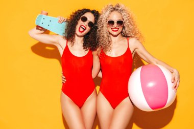 Kırmızı yaz mayo giyen iki güzel seksi hippi kadın. Saçları kıvırcık moda modeller. Stüdyoda eğleniyorlar.
