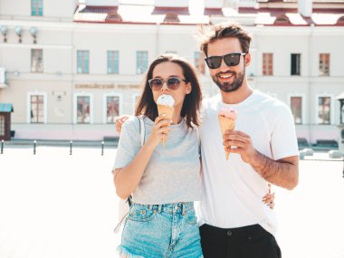 Gülümseyen güzel kadın ve yakışıklı erkek arkadaşı. Gündelik yaz kıyafetleri giymiş bir kadın. Mutlu, neşeli bir aile. Sokakta güneş gözlüklü bir çift poz veriyor. Waffle külahında lezzetli dondurma yemek.