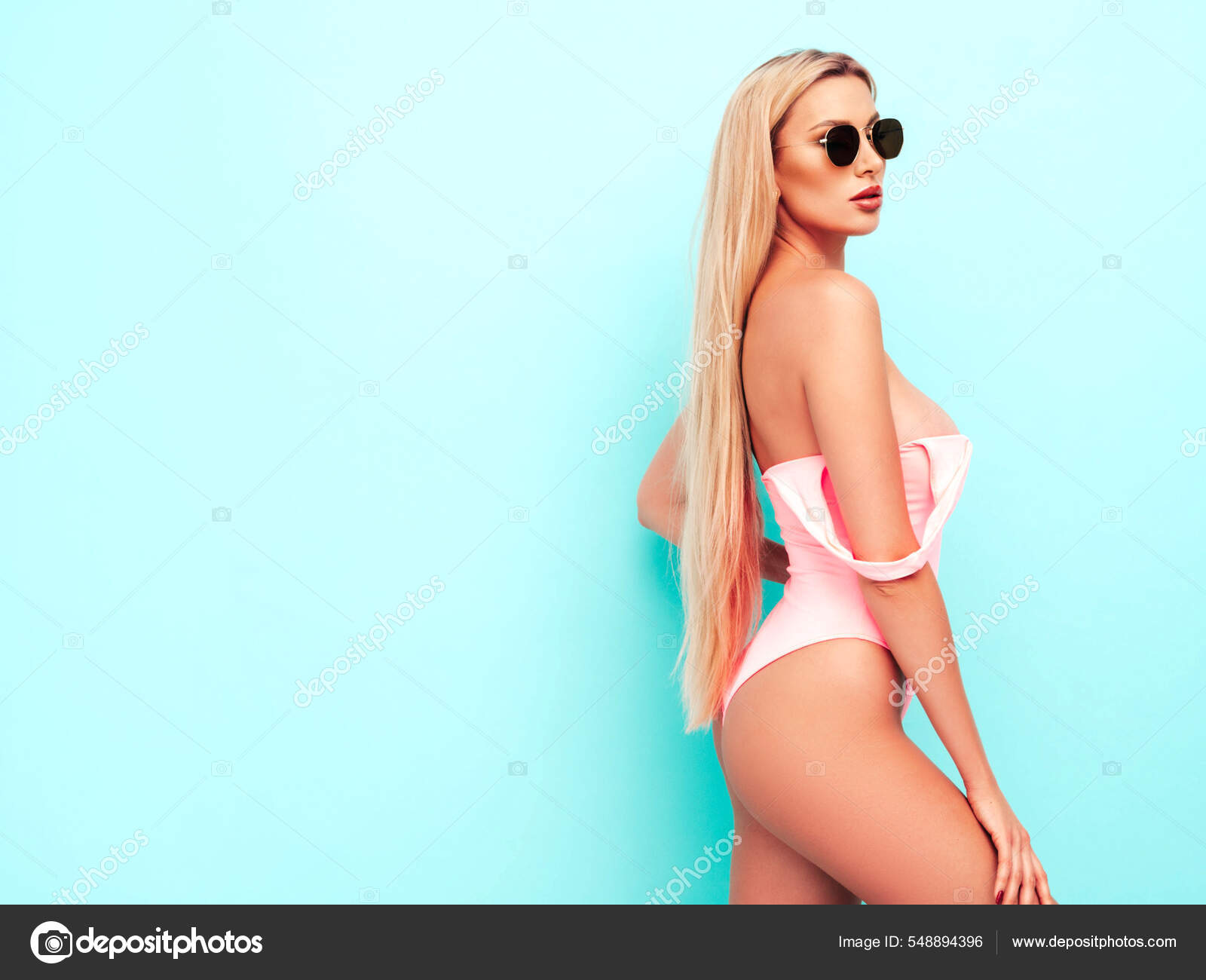 Foto de Portrait of young beautiful sexy woman with large breasts. Carefree  model wearing pure red lingerie. Hot tanned blonde posing near wall in  studio in summer swimwear bathing suit do Stock