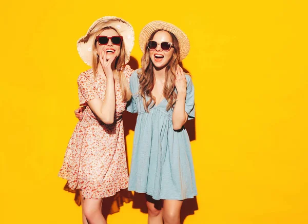 流行の夏のドレスで2人の若い美しい笑顔ブルネットのヒップスター女性 黄色の壁の近くにポーズセクシーな屈託のない女性 楽しい正のモデル 陽気で幸せ 帽子とサングラスで — ストック写真
