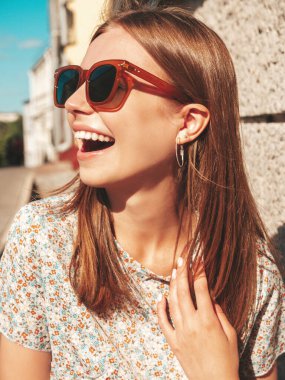 Moda kıyafetleri içinde gülümseyen genç ve güzel bir hippi kadın. Günbatımında sokakta poz veren kaygısız seksi kadın. Açık havada pozitif model. Neşeli ve mutlu güneş gözlükleriyle
