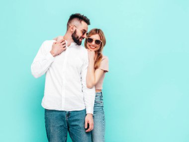 Seksi, gülümseyen güzel kadın ve yakışıklı erkek arkadaşı. Mutlu mutlu aile stüdyoda mavi duvarın yanında hassas anlar yaşıyor. Saf, neşeli modeller sarılıyor. Neşeli ve mutlu