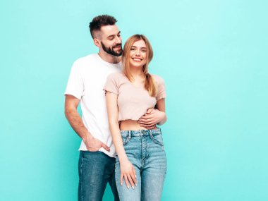 Seksi, gülümseyen güzel kadın ve yakışıklı erkek arkadaşı. Mutlu mutlu aile stüdyoda mavi duvarın yanında hassas anlar yaşıyor. Saf, neşeli modeller sarılıyor. Neşeli ve mutlu