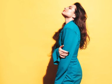 Modaya uygun mavi takım elbise giyen güzel esmer bir kadının yüksek moda portresi. Stüdyoda poz veren seksi manken. Sarıda soyutlanmış şık bir kadın.