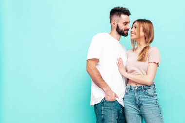 Seksi, gülümseyen güzel kadın ve yakışıklı erkek arkadaşı. Mutlu mutlu aile stüdyoda mavi duvarın yanında hassas anlar yaşıyor. Saf, neşeli modeller sarılıyor. Neşeli ve mutlu