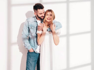 Seksi, gülümseyen güzel kadın ve yakışıklı erkek arkadaşı. Mutlu mutlu aile stüdyoda beyaz duvarın yanında hassas anlar yaşıyor. Saf, neşeli modeller sarılıyor. Güneş gözlükleriyle