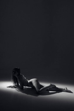 Kahverengi uzun kıvırcık saçlı, beyaz elbiseli, bronz tenli uzun bacaklı, ince vücutlu, arka planda güneş ışığı altında oturan çekici bir kadın modeli. Güzel, zarif bir vücut konsepti, pozitif, sağlıklı bir yaşam tarzı.