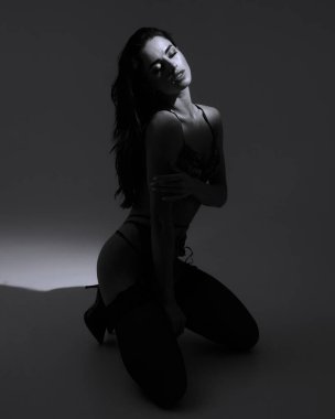 Siyah tasarımcı iç çamaşırı giymiş genç ve güçlü sporcu kadın 2022. Güzel, zarif bir figür, vücut pozitifliği, sağlıklı yaşam tarzı. Bronzlaşmış kadın vücudu. Yumuşak gri bir arkaplanda izole edilmiş.