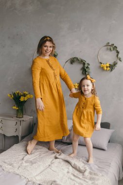 Çamaşır elbiseli anne ve kız dönüyor, gülüyor ve eğleniyorlar.