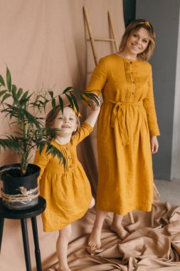 Çamaşır elbiseli anne ve kız dönüyor, gülüyor ve eğleniyorlar.