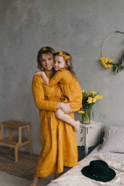 Bir anne kızını kollarına alır ve keten elbiseli bir anne ve kıza hayran olur. Döner, güler ve bir buket narsist çiçeğinin yanında eğlenir.