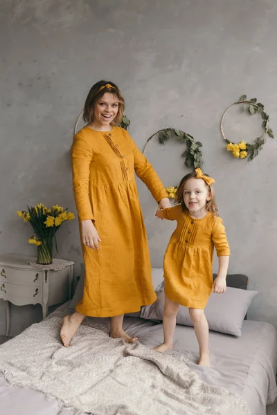 Çamaşır elbiseli anne ve kız dönüyor, gülüyor ve eğleniyorlar.