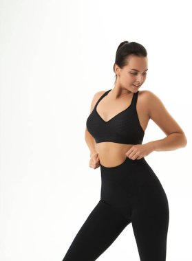 Spor giyim bölümünde ince, bronzlaşmış genç bir kadın vücudu. Mükemmel vücut, yağ yok, motivasyon yok, sağlıklı yaşam tarzı, fitness rutini. İzole edilmiş beyaz arkaplan. 