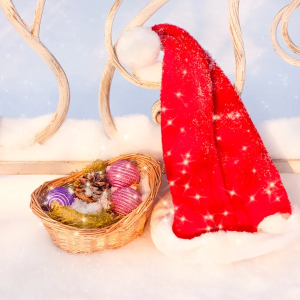 在雪上的圣诞装饰品与圣诞老人的帽子 — 图库照片