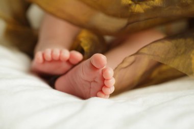 Yeni doğmuş bebek ayakları beyaz battaniyenin altında, bebek çıplak ayaklarının kapanışı