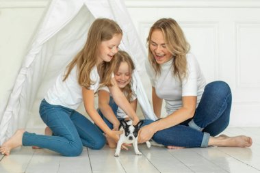 Lovely mother and two daughter and little dog pet indoor. Happy family portrait