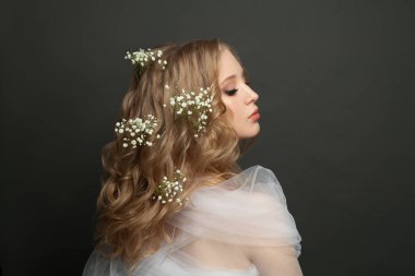 Güzel, genç ve güzel bir kadın. Uzun, sağlıklı kıvırcık saçları ve siyah üzerinde beyaz çiçekleri var.