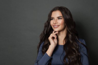 Çekici bir kadın yukarı bakıyor ve gülümsüyor. Esmer güzel, uzun kıvırcık saçlı, esmer.