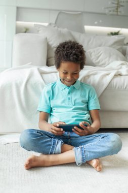 Neşeli şirin çocuk akıllı telefon kullanırken eğleniyor.