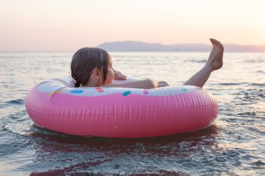 Yaz deniz dalgalarında şişme yüzüklerin üzerinde süzülen rahatlatıcı küçük kız