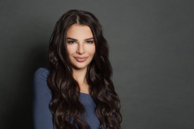 Uzun saçlı güzel bir esmer. Klasik kıvırcık saçlı güzel kadın gülümsüyor.