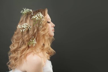 Doğal makyajlı ve uzun kıvırcık saçlı çekici bir kadın profili.