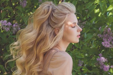 Uzun ve parlak dalgalı saçlı sarışın kadın. Açık havada kıvırcık saçlı güzel bir manken kadın. .