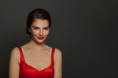 Siyah arkaplanda kırmızı ruj ve makyaj malzemesi olan çekici bir kadın..