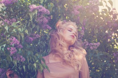 Güzel bir kadın açık havada bahar çiçeklerinde dinleniyor.