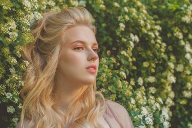 Yeşil bahar arka planında uzun dalgalı saçları olan güzel genç bir kadın.