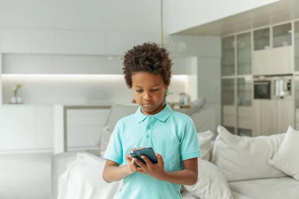 Niño Serio Con Teléfono Casa —  Fotos de Stock