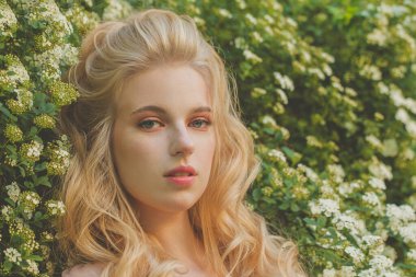 Güzel, kıvırcık saçlı, bahar doğasında uzun kıvırcık saçlı genç bir kadının moda fotoğrafını çek.