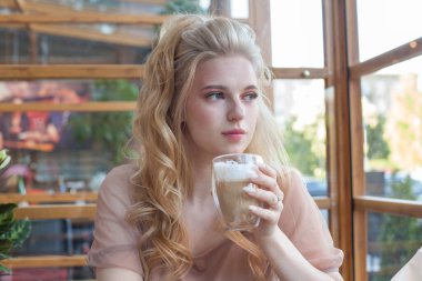 Güzel kadın içeride kahve içiyor.