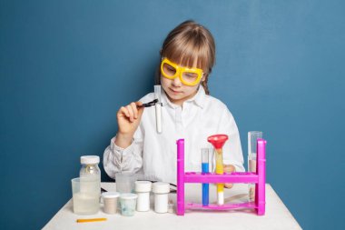 Laboratuvarda kimyasal sıvıyla araştırma yapan küçük bir öğrenci.