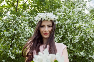 Açık havada çiçek açan neşeli esmer kadın.