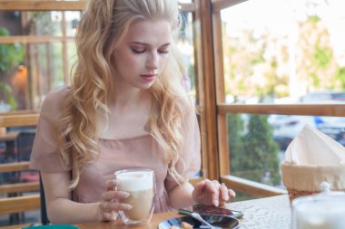 Kafede kahve içen ve cep telefonu kullanan öğrenci kadın.