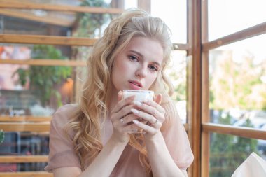 Güzel genç bayan bir kafede kahve içiyor.