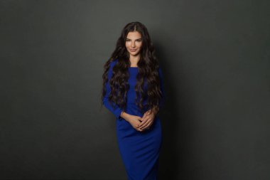 Gri arka planda duran çekici model kadın. Mavi elbiseli, uzun saçlı mükemmel bir kadının stüdyo fotoğrafı.