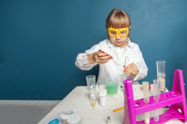 Akıllı kız öğrenci öğrenimi, kimyasal deney yapıyor ve fen dersinde deney tüpünü elinde tutuyor. Eğitim ve bilim konsepti