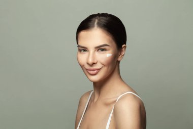 Temiz cildinde krem olan sevimli, gülümseyen spa modeli bir kadın. Güzellik portresi.