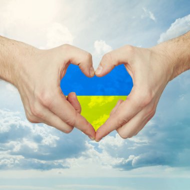 Ukrayna bayrağıyla gökyüzü bulutlarına karşı kalp şekli veren erkek eller.