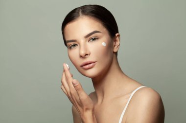 Genç mükemmel spa modeli kadın mükemmel cildine krem sürüyor. Güzellik portresi.