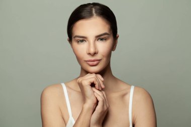 Temiz ciltli güzel bir spa modeli. Esmer kadın kameraya bakıyor ve gülümsüyor. Gençlik ve cilt bakımı kavramı.