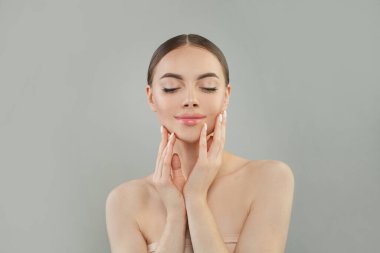 Hoş bir genç kadın yüzüne dokunuyor, kolları kapalı, gözleri kapalı.