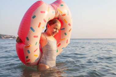 Sevimli çocuk gülüyor ve denizde eğleniyor.